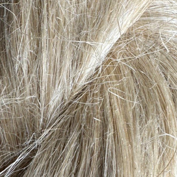 Närbild av en docka med naturligt lingarn, lämpligt för traditionellt hantverk, käpphästar och dockhår.